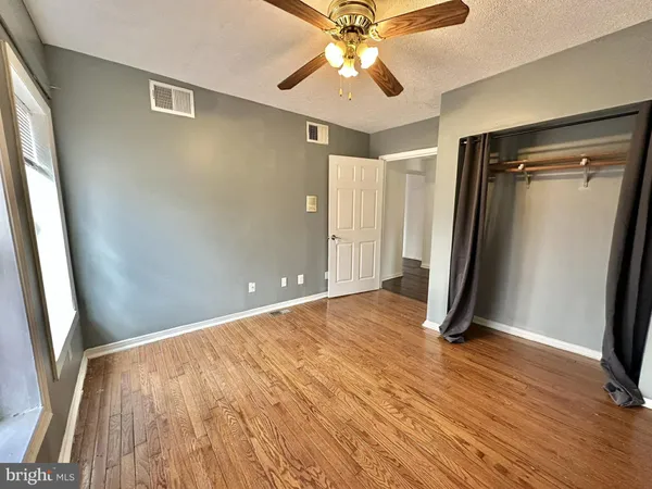 a view of a room with wooden floor and a ceiling fan