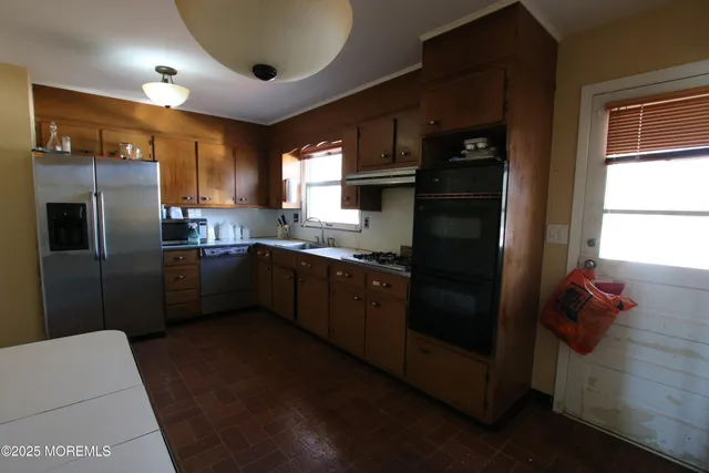 a kitchen with stainless steel appliances granite countertop a refrigerator a sink a stove and a refrigerator