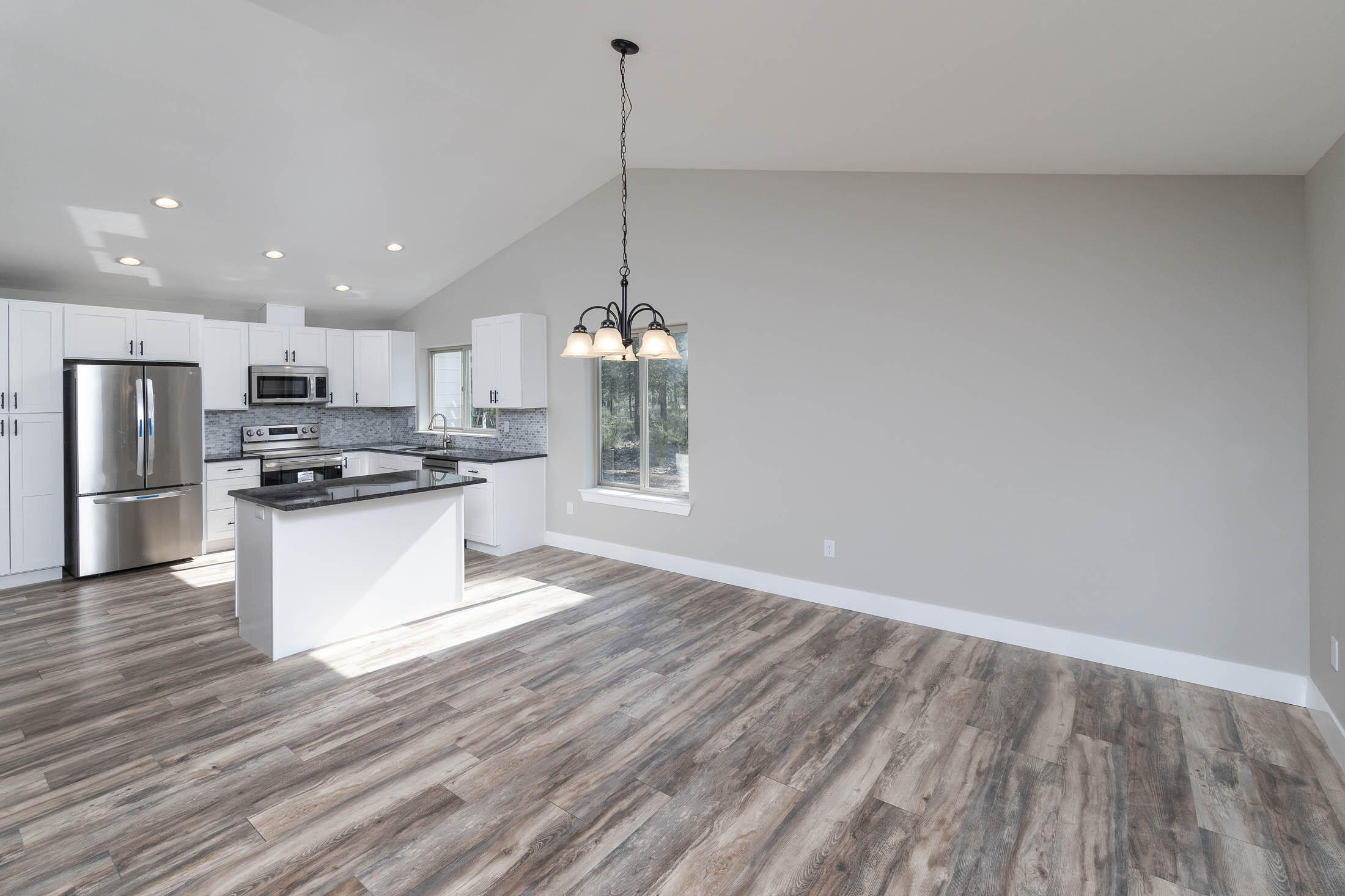 17163 Bakersfield Road Bend, OR 97707 - Photo 7 of 22 a kitchen with stainless steel appliances granite countertop a sink a microwave oven a refrigerator and white cabinets with wooden floor