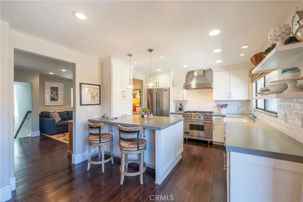 a kitchen with stainless steel appliances kitchen island granite countertop a stove top oven a sink a dining table and chairs