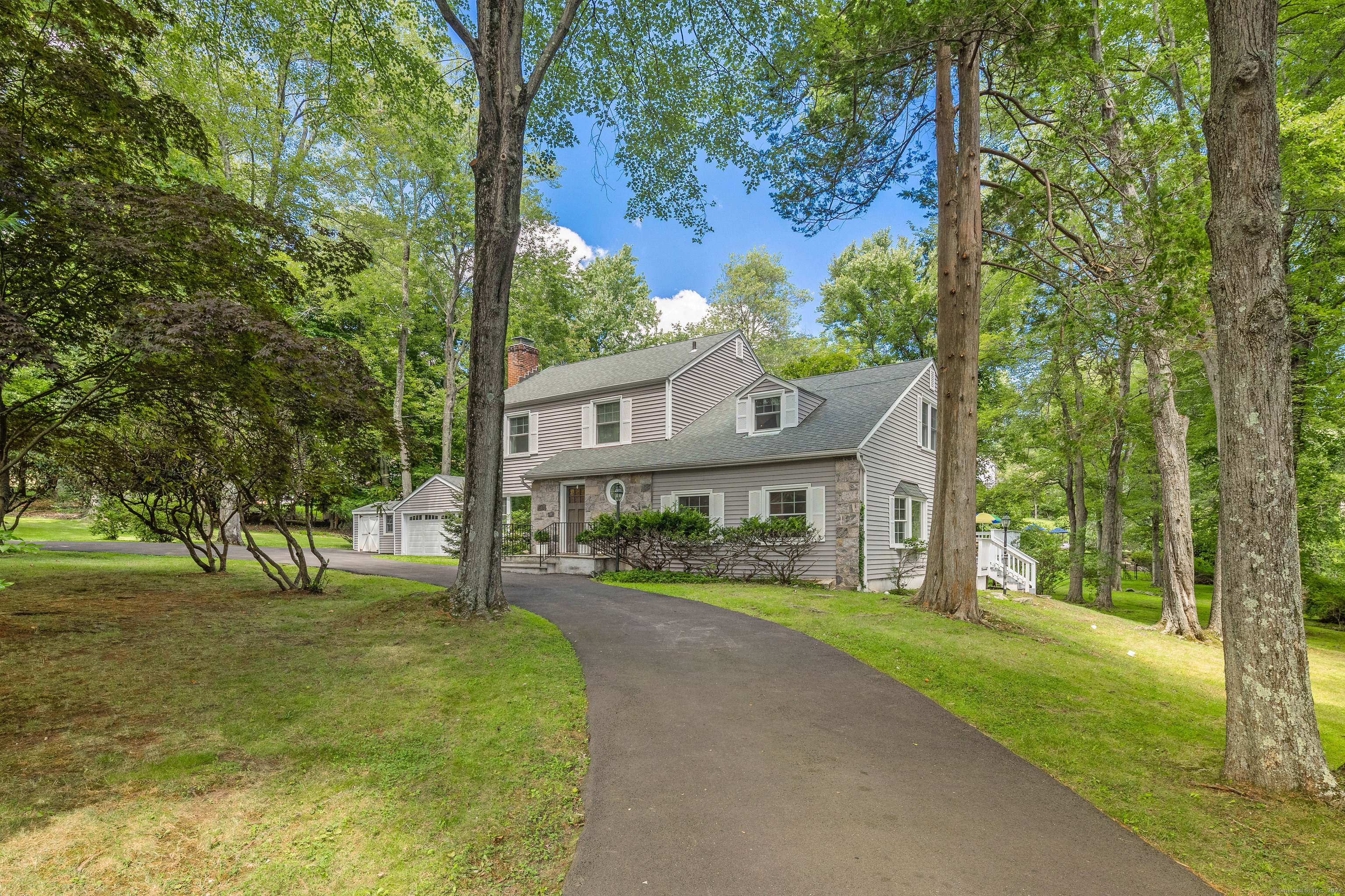 a view of house in front of a big yard with large trees