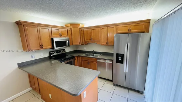 a kitchen with a refrigerator a microwave a sink and cabinets