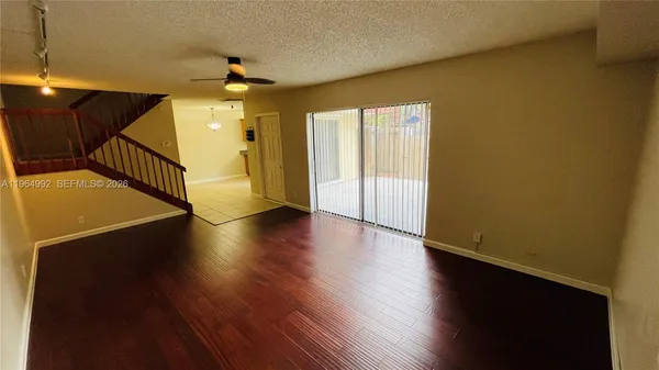 a view of a room with wooden floor a ceiling fan and windows