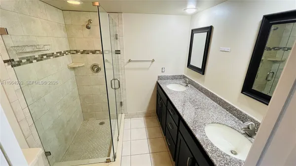 a bathroom with a granite countertop shower sink and mirror