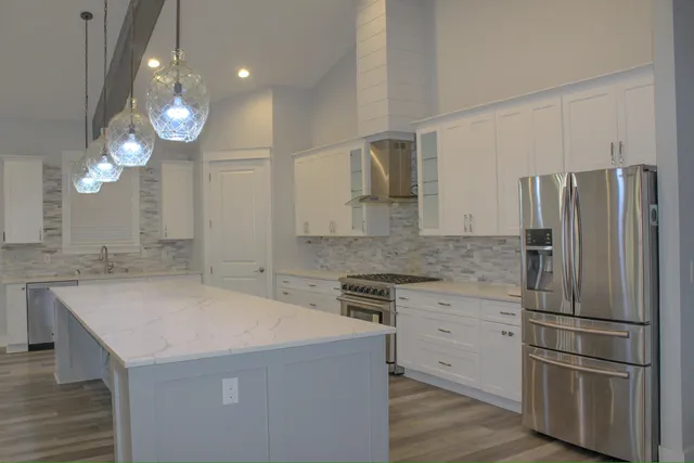 a kitchen with stainless steel appliances granite countertop a sink a stove a refrigerator a center island and wooden floor