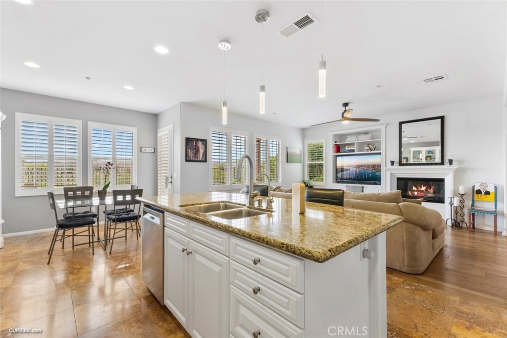 a very nice looking kitchen with granite countertop a large center island and a table in it