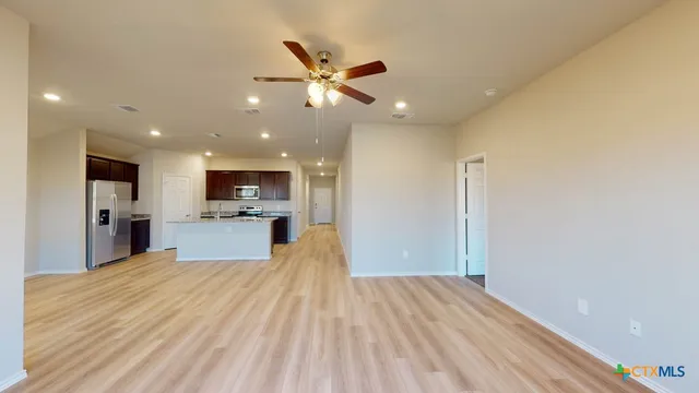 a view of a kitchen with kitchen island a sink wooden floor and stainless steel appliances