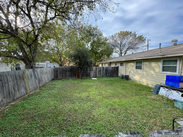 a view of a backyard with table and chairs and a large tree