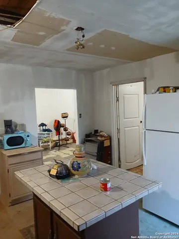a view of a kitchen island with a sink dishwasher stove and refrigerator with wooden floor