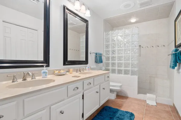 a bathroom with a double vanity sink toilet mirror and shower