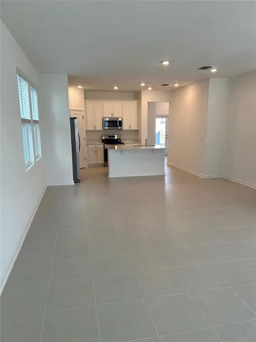 a view of empty room with kitchen view