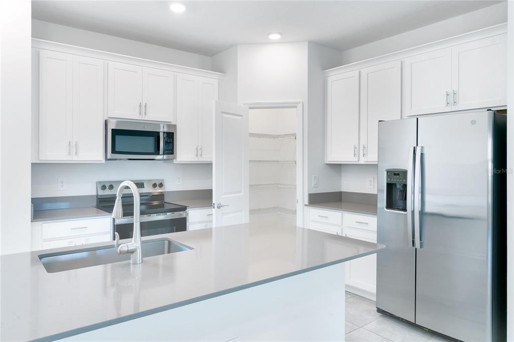 15524 Water Spring Boulevard Winter Garden, FL 34787 - Photo 10 of 40 a kitchen with stainless steel appliances a refrigerator a stove a microwave and cabinets