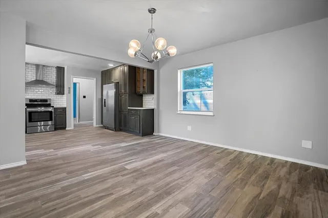 a view of an empty room with a kitchen and a window
