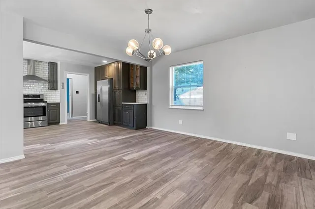 a view of an empty room with a window and a kitchen