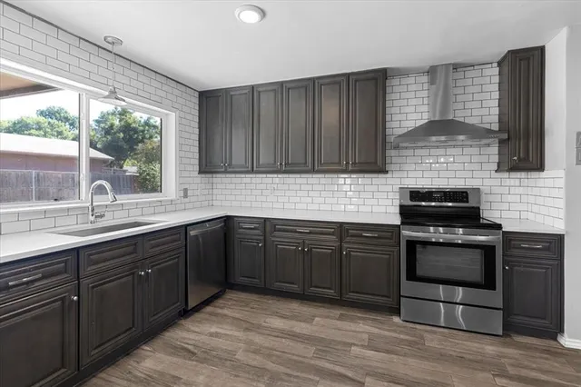 a kitchen with stainless steel appliances granite countertop a stove a sink and a microwave