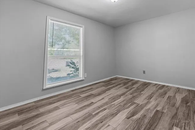 a view of empty room with window and wooden floor
