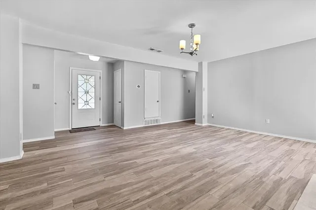 a view of an empty room with window and wooden floor