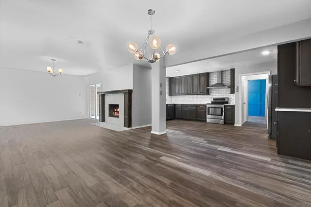 a view of a livingroom with a chandelier wooden floor and a kitchen