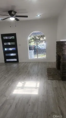 an empty room with wooden floor chandelier fan and windows