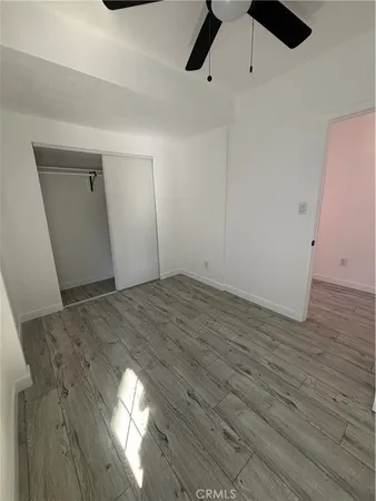 an empty room with wooden floor cabinet and windows