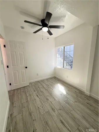 an empty room with wooden floor fan and windows