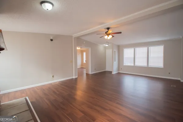 a view of an empty room with window and wooden floor