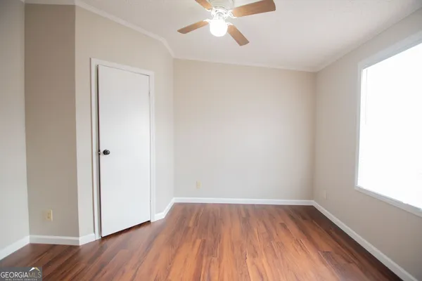 an empty room with wooden floor and windows