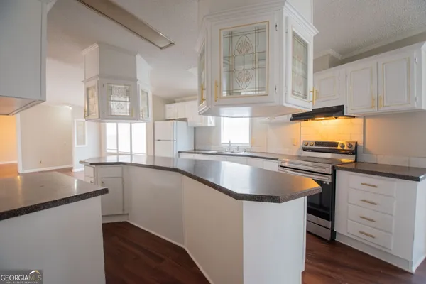 a kitchen with granite countertop a sink a stove and cabinets