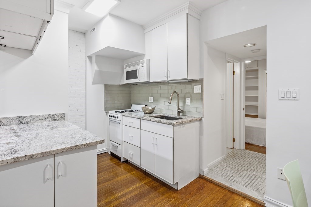 338 Beacon Street, Unit A Boston, MA 02116 - Photo 9 of 17 a kitchen with granite countertop white cabinets and white appliances