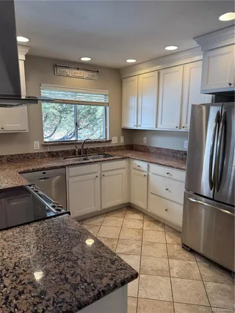 a kitchen with stainless steel appliances granite countertop a sink stove refrigerator and cabinets