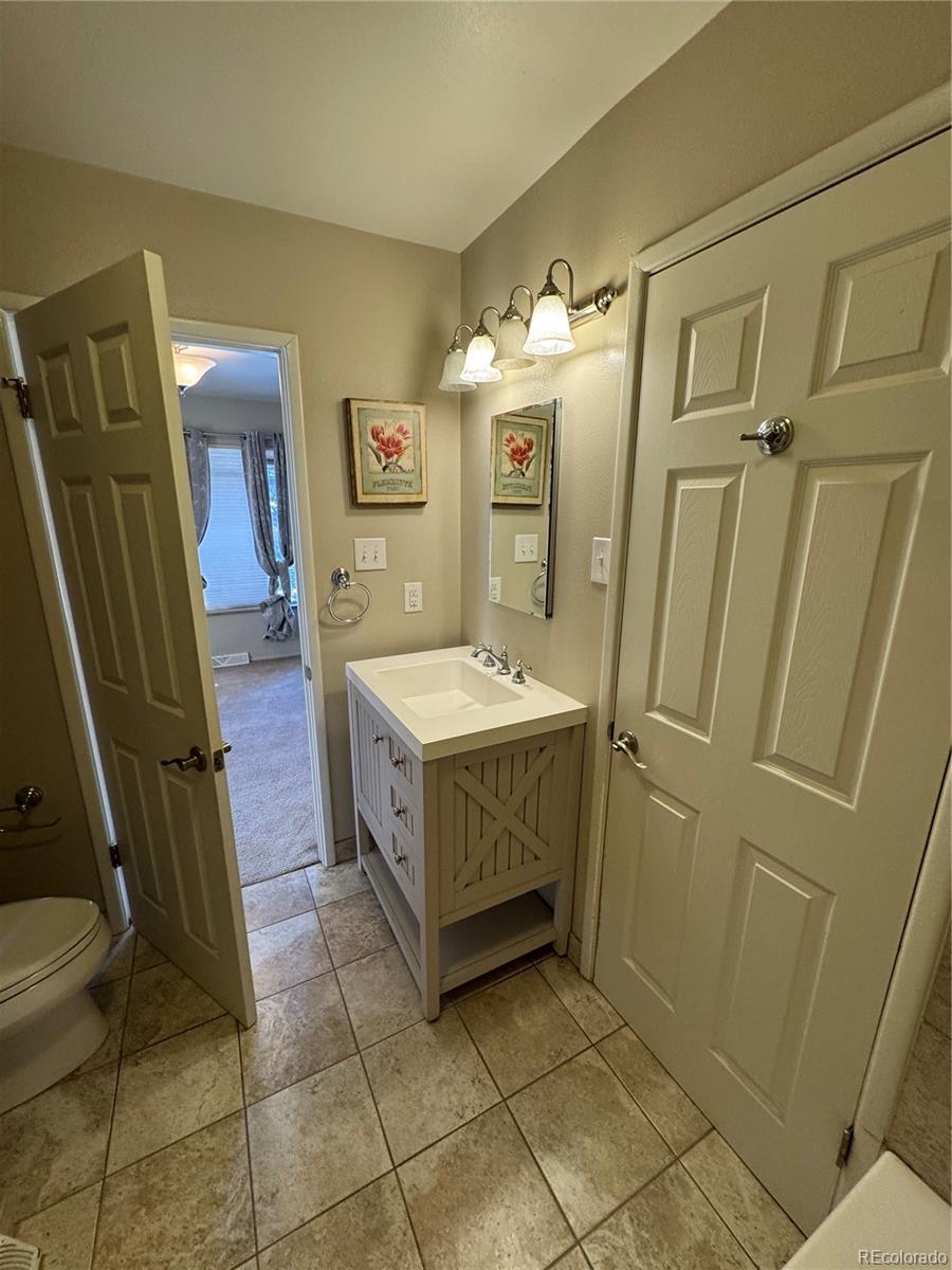 2524 South Oneida Street Denver, CO 80224 - Photo 10 of 11 a bathroom with a sink a toilet and a mirror