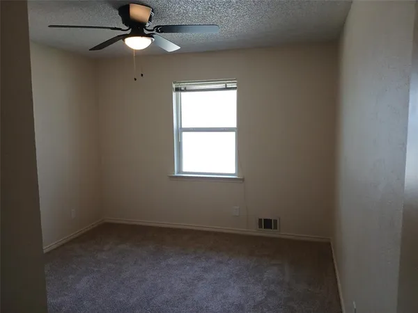 an empty room with a window and a fan