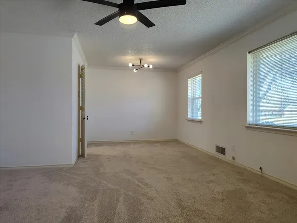 en empty room with windows and ceiling fan