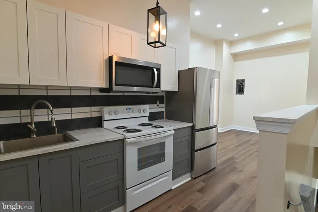 a kitchen with stainless steel appliances granite countertop a sink a stove a microwave a refrigerator a counter space and cabinets