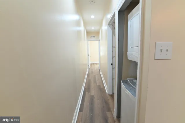 a view of a hallway with wooden floor and a bathroom