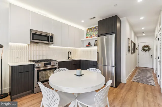 a kitchen with stainless steel appliances a stove a sink a microwave a refrigerator a kitchen island and chairs