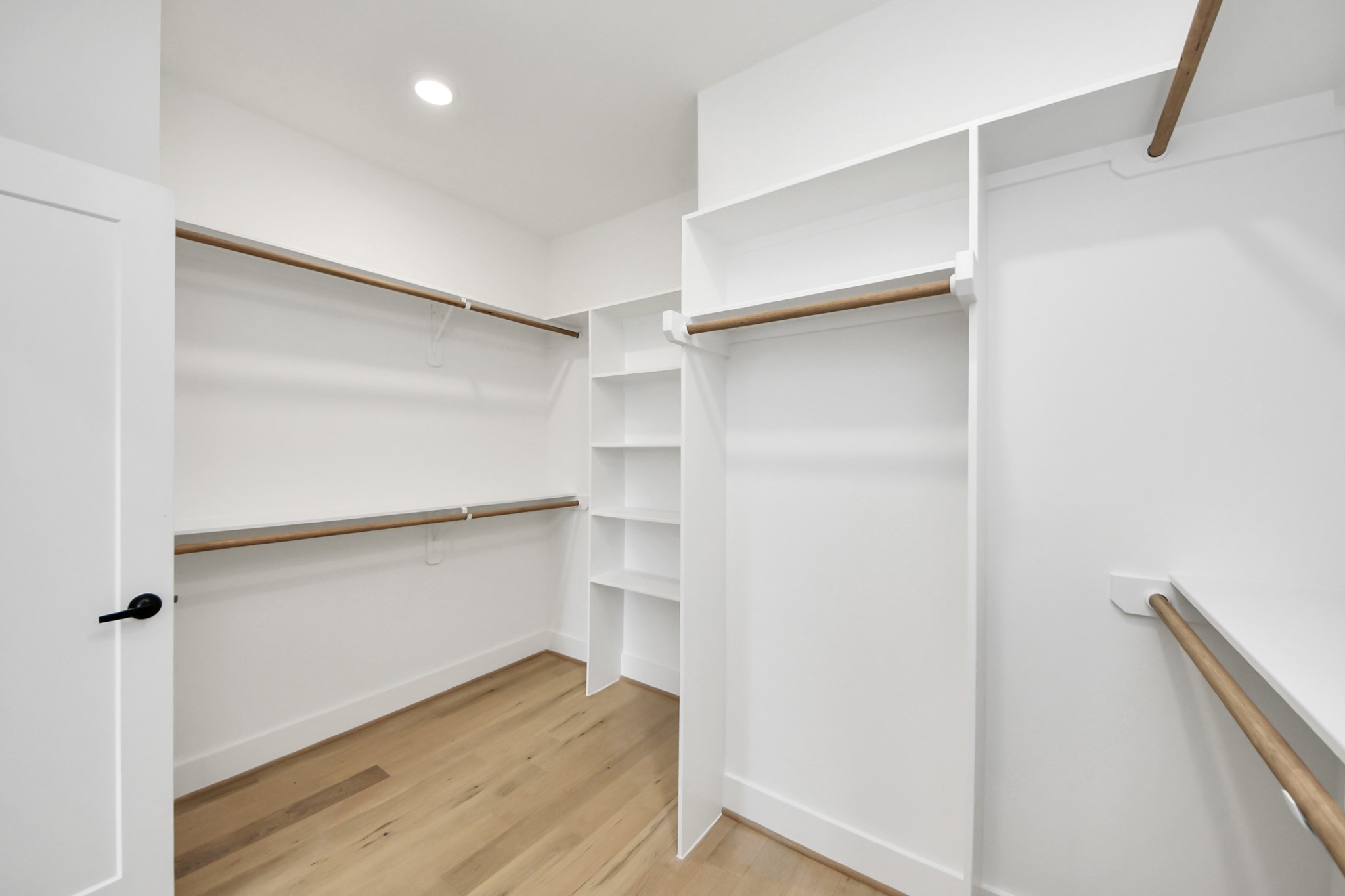 723 Marcella Street, Unit A Houston, TX 77091 - Photo 19 of 24 Step into your spacious, clean-lined owners retreat dressed walk-in closet featuring built-in white shelving on one side and multiple hanging rods for ample clothing storage.