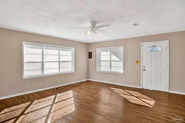 a view of an empty room with wooden floor and a window