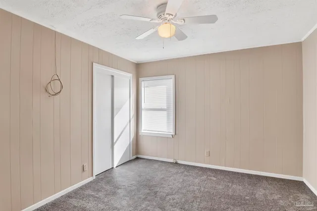 an empty room with windows and fan