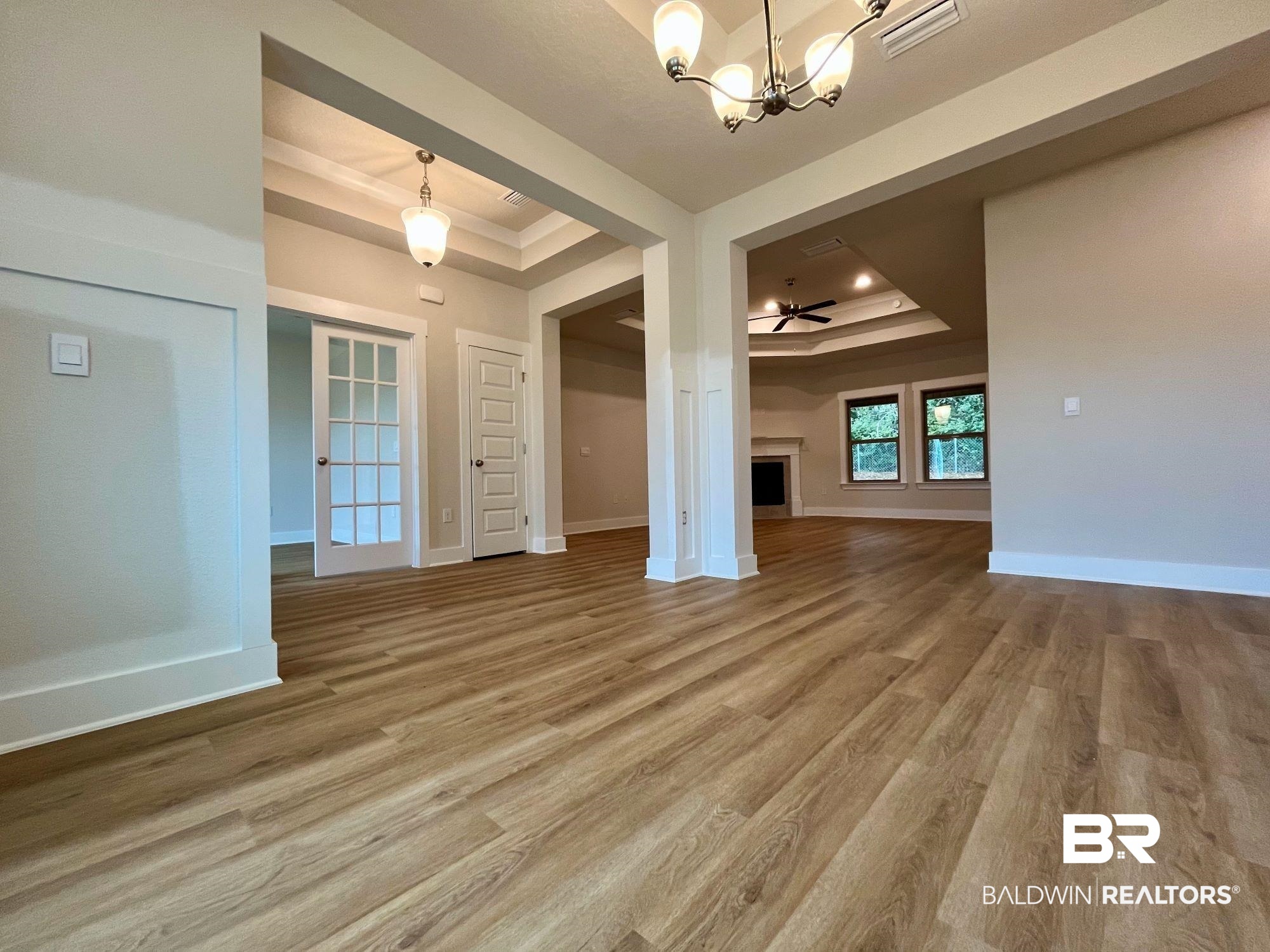330 Barndling Street Fairhope, AL 36532 - Photo 8 of 31 Unfurnished living room featuring a tray ceiling, wood-type flooring, and ceiling fan with notable chandelier
