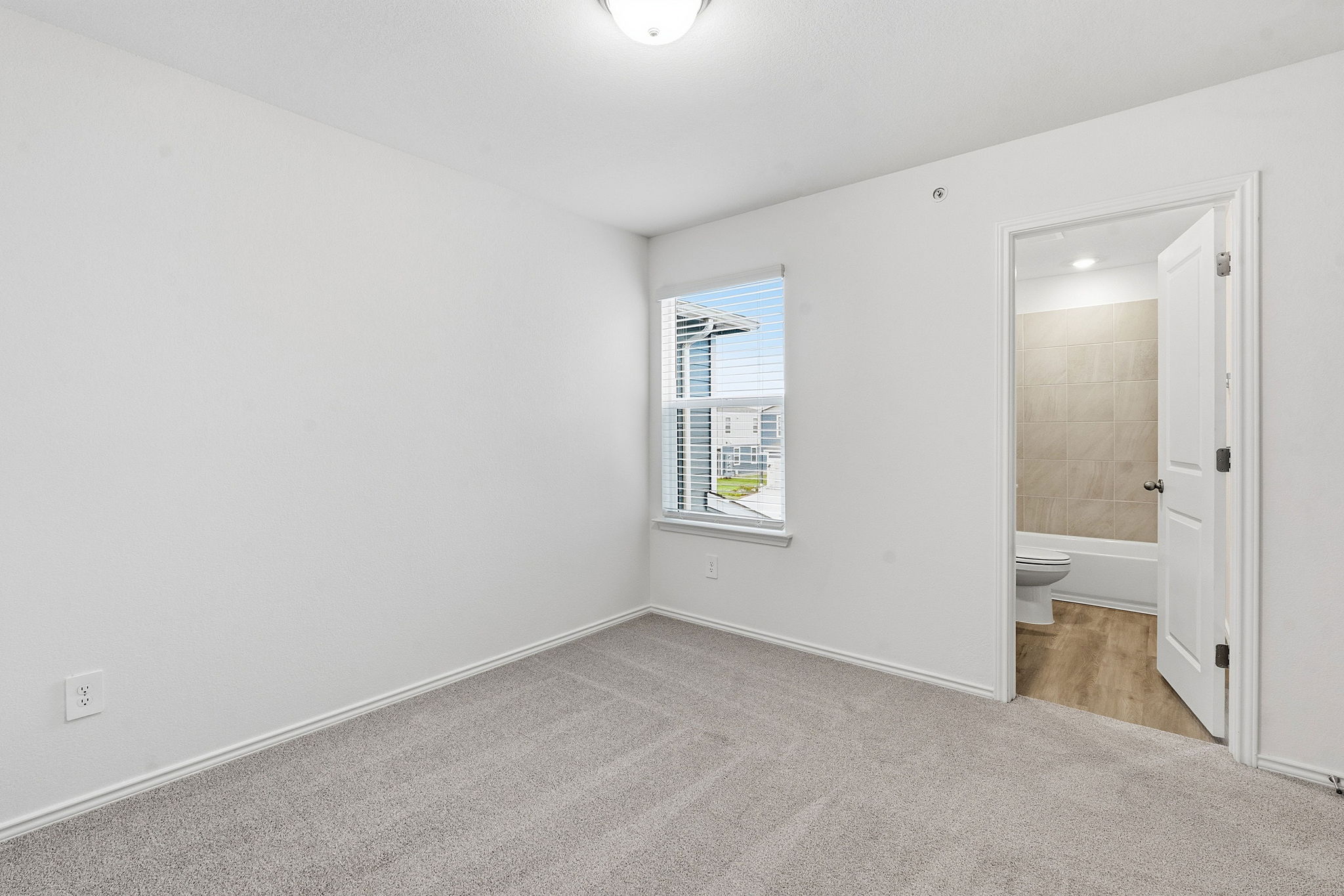 164 Cinnabar Lane, Unit 4 Kyle, TX 78640 - Photo 17 of 23 Neutral-toned carpeted room featuring a window with horizontal blinds and white trim