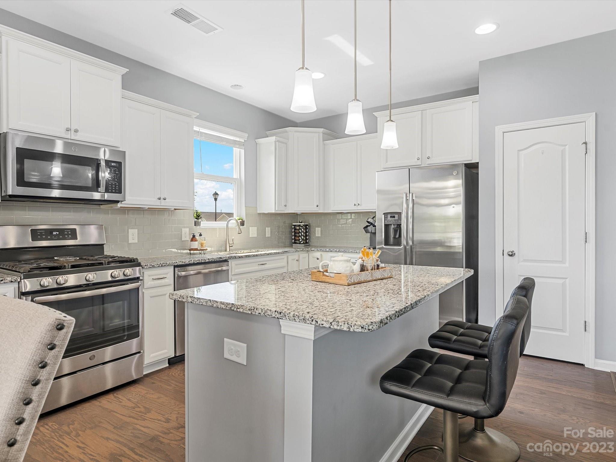 3187 Bridgewater Street Lancaster, SC 29720 - Photo 12 of 37 a kitchen with stainless steel appliances granite countertop a stove a refrigerator a sink dishwasher a dining table and chairs with wooden floor
