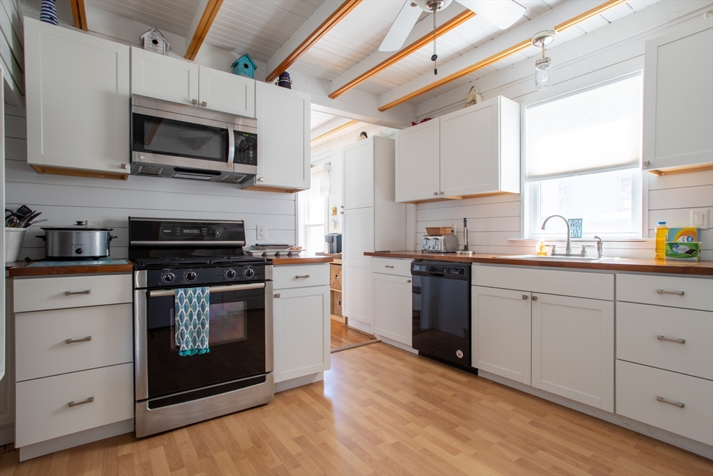 29 Commonwealth Avenue Salisbury, MA 01952 - Photo 15 of 34 a kitchen with stainless steel appliances white cabinets a sink a stove a microwave and wooden floors