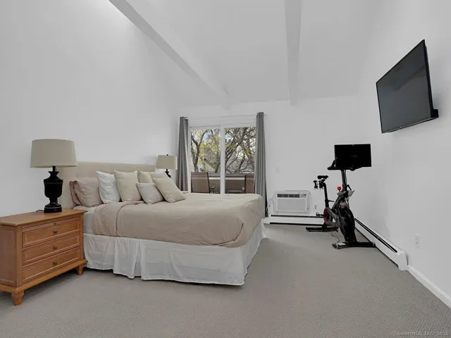 a bedroom with a bed and flat tv screen on the dresser