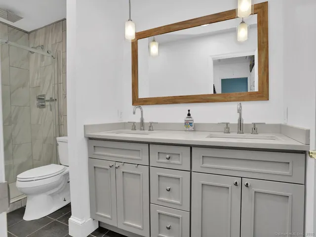 a bathroom with a granite countertop sink a toilet and a mirror