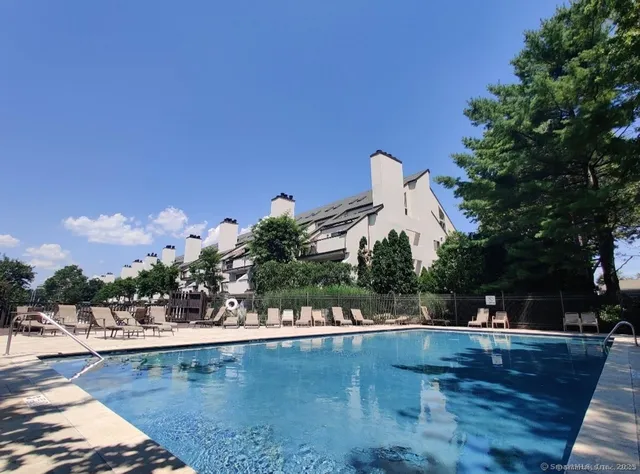 a view of a swimming pool with a bench and trees around