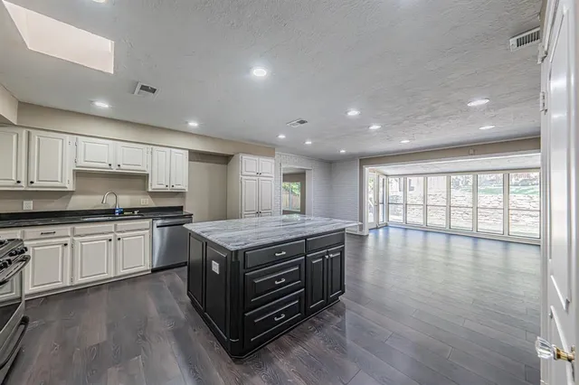 a kitchen with stainless steel appliances granite countertop a stove and a wooden floors