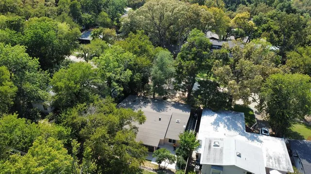 an aerial view of residential house with outdoor space and trees all around