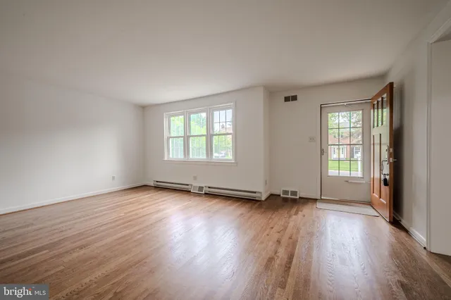 an empty room with wooden floor and windows