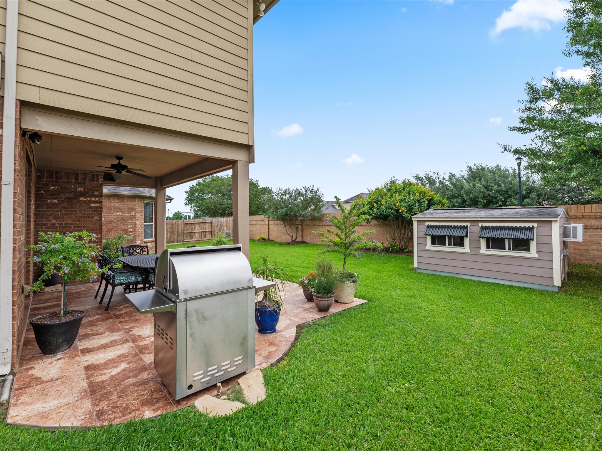 3907 Randle Ridge Court Fulshear, TX 77441 - Photo 39 of 46 Spacious backyard with a covered patio, perfect for outdoor dining and entertaining, featuring space for a grill and lush greenery. A charming shed provides extra storage or hobby space.